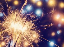 Sternwerfer _1 Eine Wunderkerze sprüht funkelnde Lichter vor einem bunten, festlichen Hintergrund